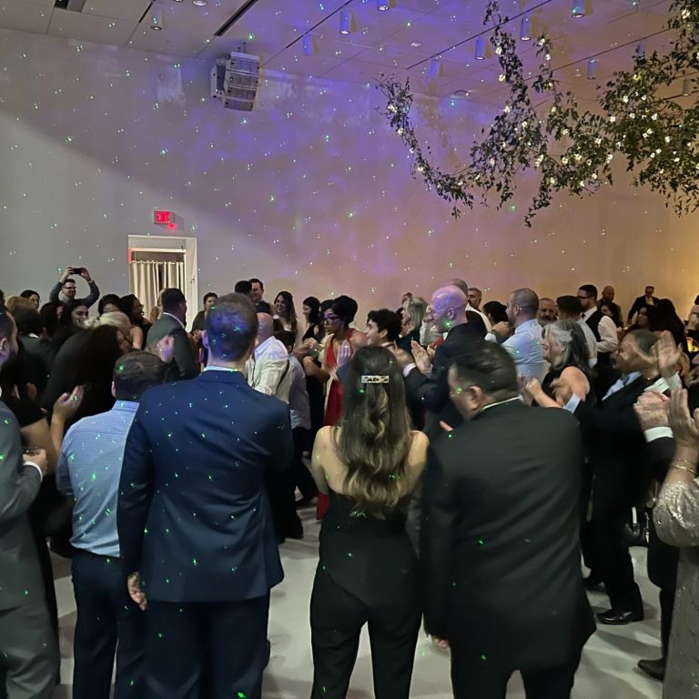 Crowd dancing at a lively event with lights and decorations.